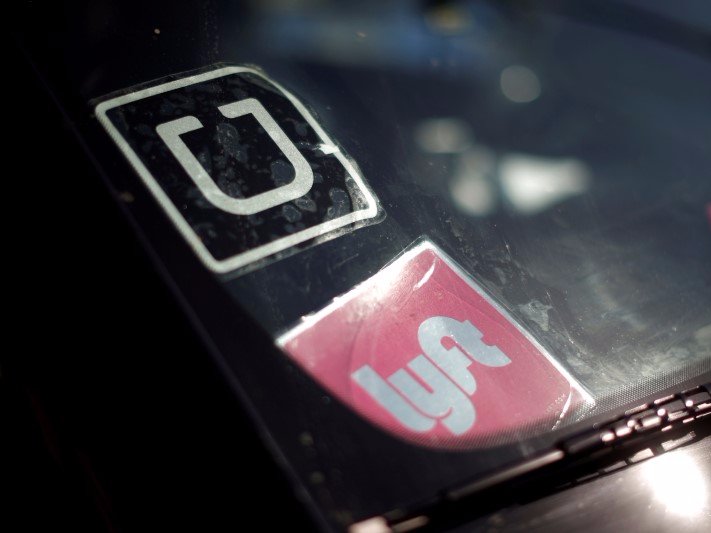 A driver displays Uber and Lyft ride sharing signs in his car windscreen in Santa Monica, California, U.S., May 23, 2016.  REUTERS/Lucy Nicholson/Files 